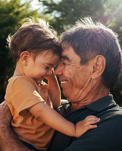 grandfather smiling and holding grandson