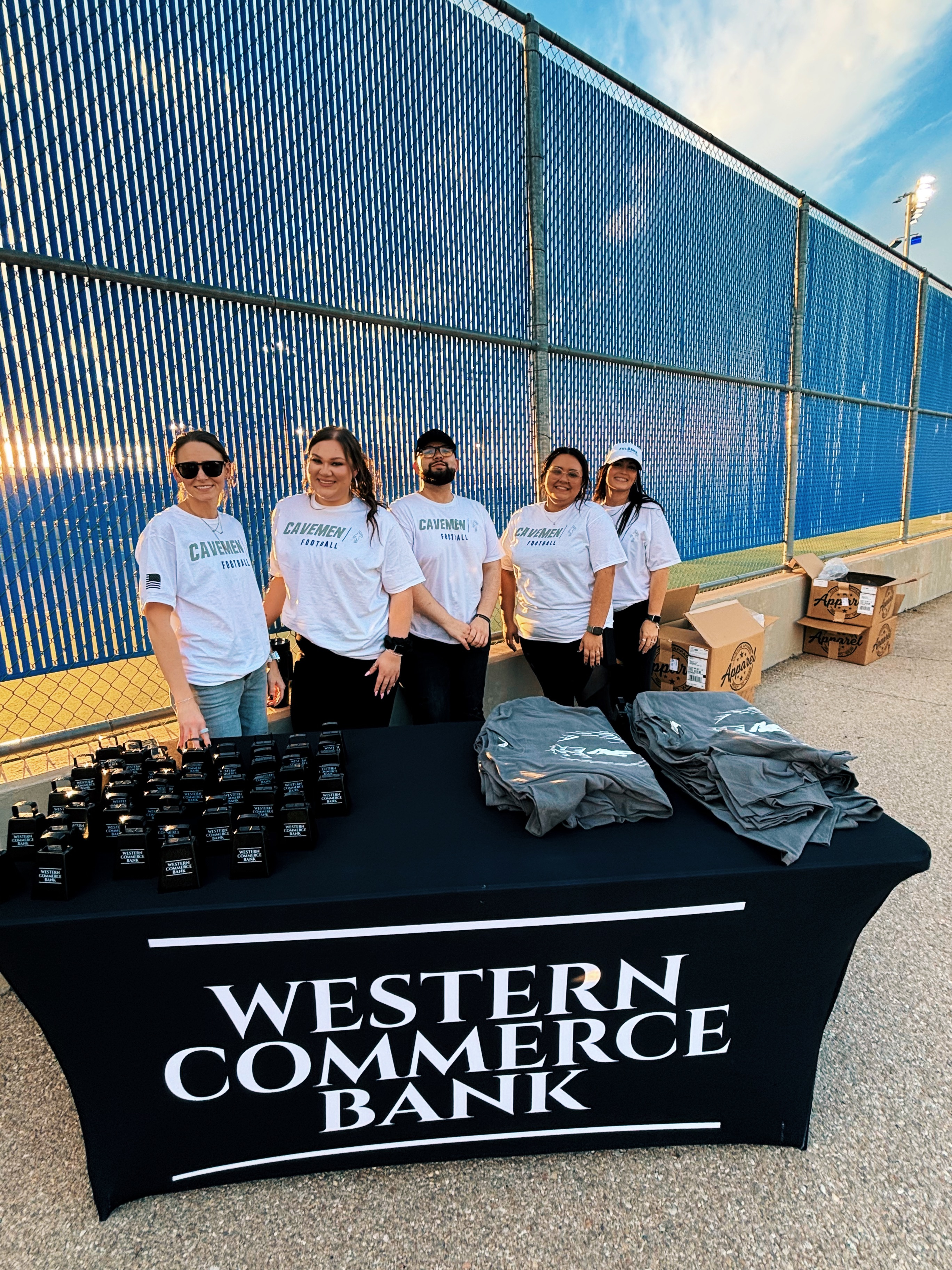 5 bank employees stand behind a table with giveaways